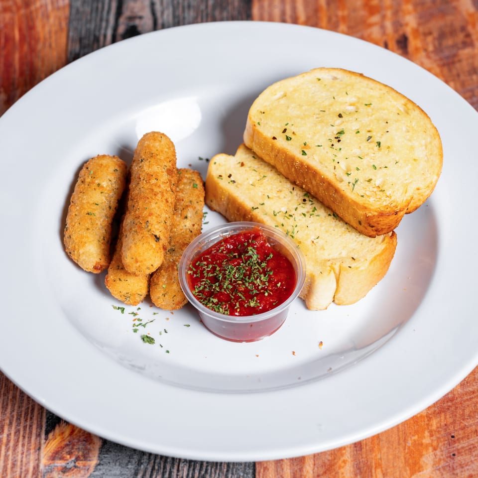 Golden mozzarella sticks, garlic bread, and a cup of marinara sauce on a white plate.
