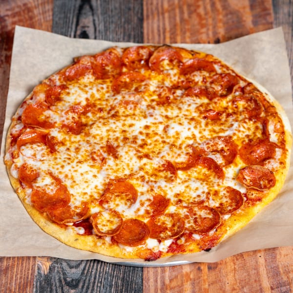 A Kozi Italian Street Food pepperoni pizza with melted cheese on parchment paper.